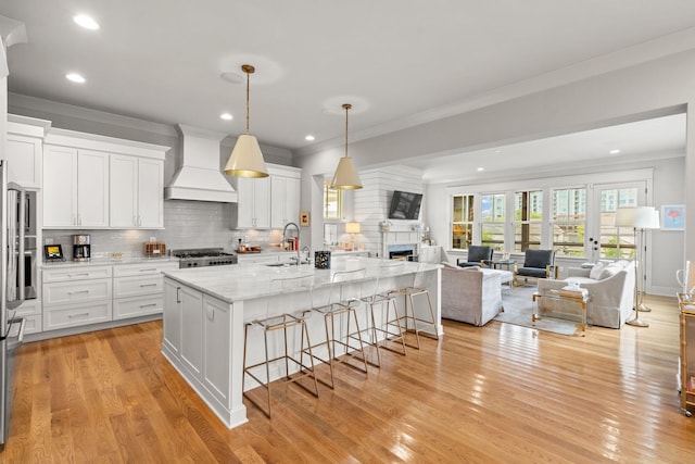 kitchen featuring decorative backsplash, ornamental molding, open floor plan, premium range hood, and a kitchen breakfast bar