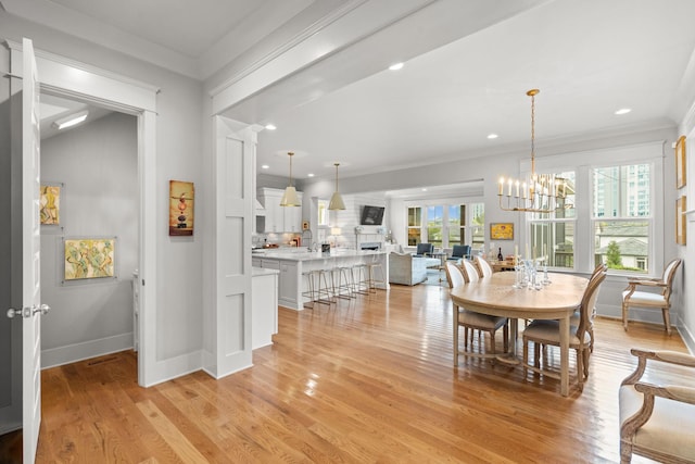 dining room featuring light wood-style floors, plenty of natural light, an inviting chandelier, and ornamental molding