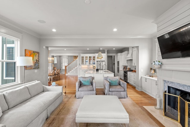 living room featuring recessed lighting, a premium fireplace, light wood finished floors, and stairs