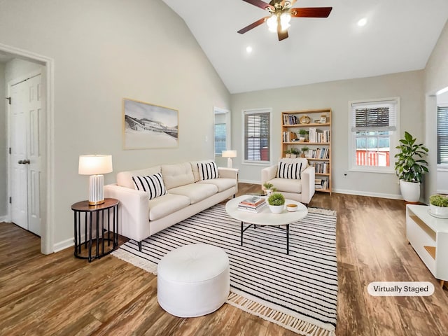 living area with high vaulted ceiling, wood finished floors, and baseboards