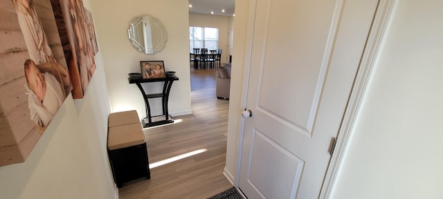 corridor with light wood-type flooring and baseboards