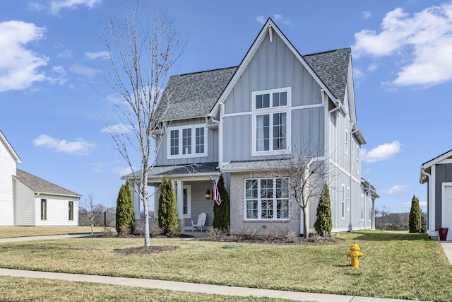 view of front of house featuring a front lawn, board and batten siding, and roof with shingles