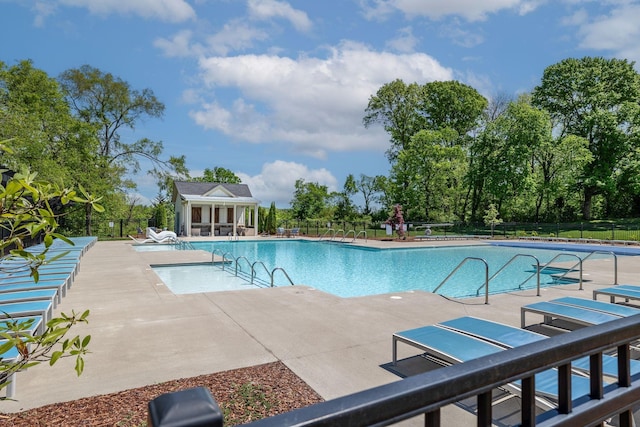 pool with fence, an outbuilding, and a patio