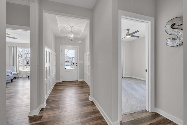 foyer entrance with a chandelier, dark wood-style flooring, a healthy amount of sunlight, and baseboards