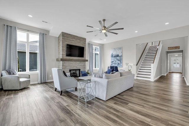 living area featuring recessed lighting, a fireplace, wood finished floors, visible vents, and stairway