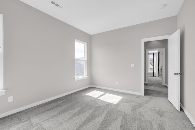 carpeted empty room with visible vents and baseboards