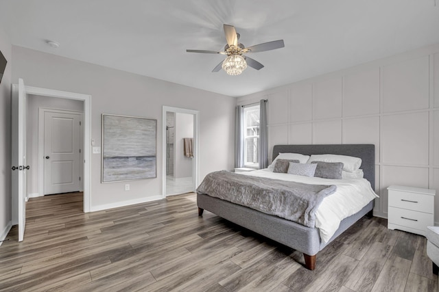 bedroom with ceiling fan, connected bathroom, baseboards, and wood finished floors