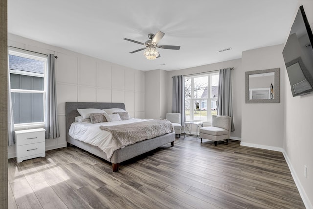 bedroom with baseboards, wood finished floors, visible vents, and a ceiling fan