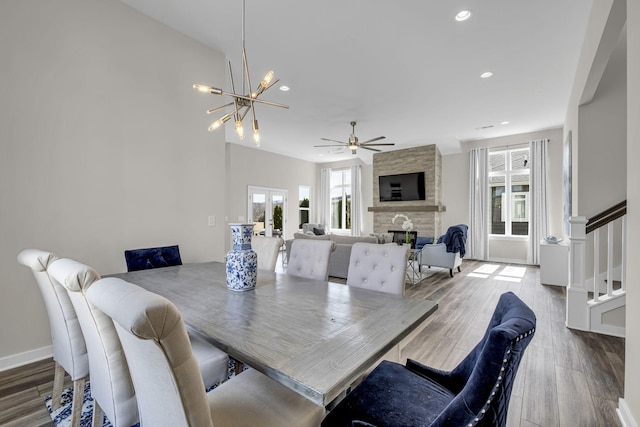 dining space with recessed lighting, ceiling fan with notable chandelier, a fireplace, wood finished floors, and stairway