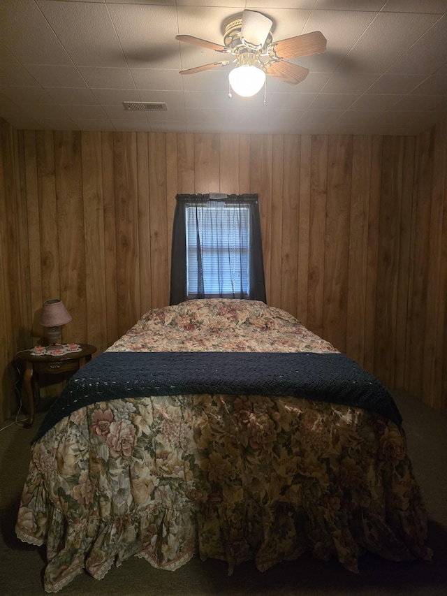 bedroom with visible vents, wood walls, and ceiling fan