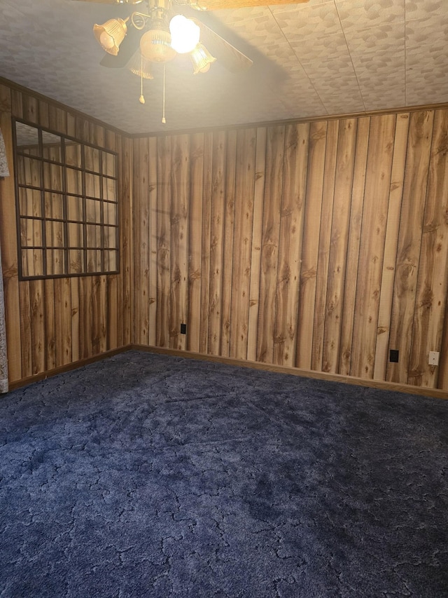 carpeted empty room featuring a ceiling fan and wooden walls