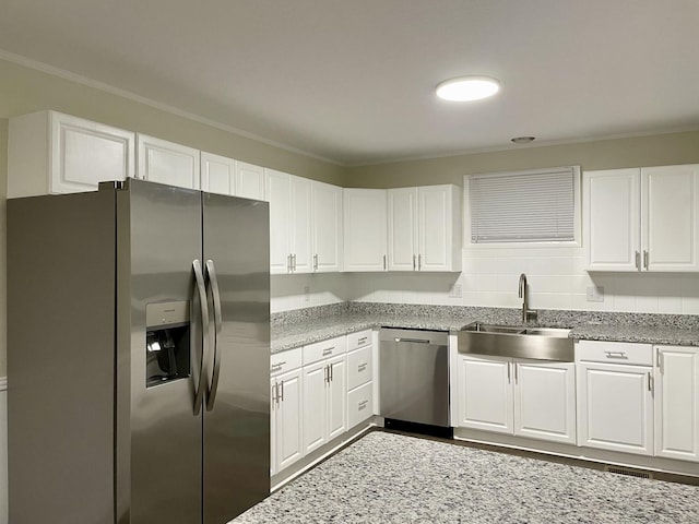 kitchen featuring stainless steel appliances, white cabinets, a sink, and backsplash