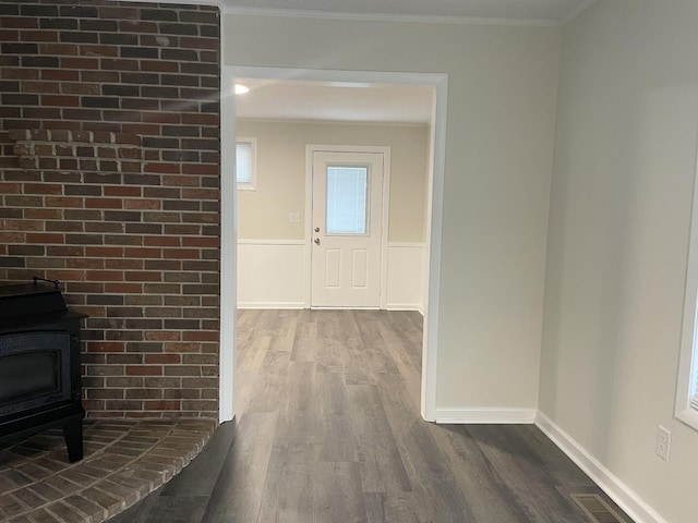 hallway featuring dark wood-style flooring, visible vents, crown molding, and a wainscoted wall