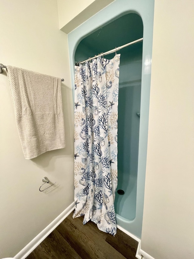 bathroom with a shower with shower curtain, wood finished floors, and baseboards