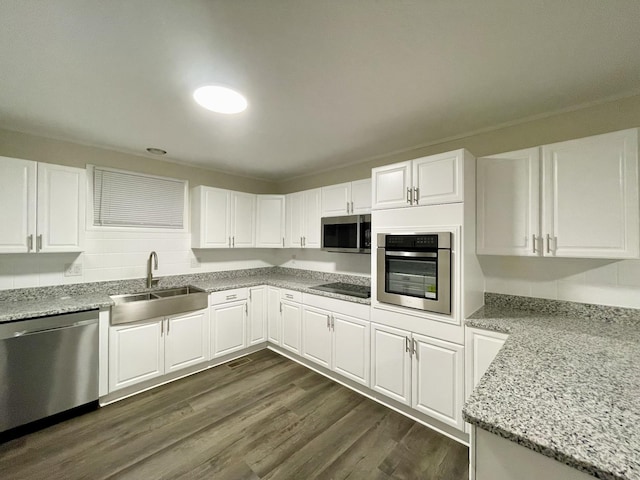 kitchen featuring dark wood-style flooring, appliances with stainless steel finishes, white cabinets, a sink, and light stone countertops