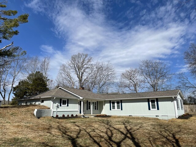 view of front of property with crawl space, brick siding, a chimney, and a front yard