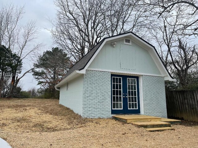 view of outbuilding with french doors, an outdoor structure, and fence