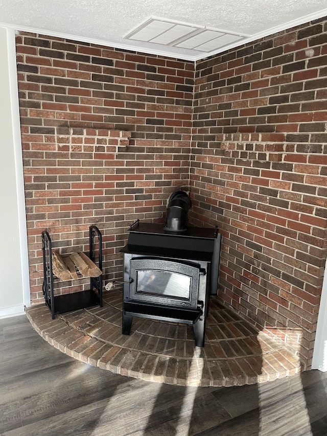 interior details with a textured ceiling, wood finished floors, and a wood stove