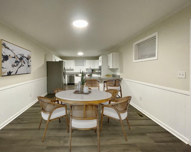 dining space with dark wood-type flooring, a wainscoted wall, and visible vents