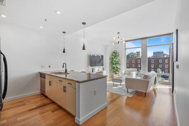 kitchen featuring light wood-style flooring, a sink, a wall of windows, dishwasher, and a peninsula