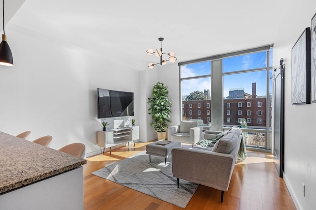 living room with floor to ceiling windows, a notable chandelier, baseboards, and wood finished floors