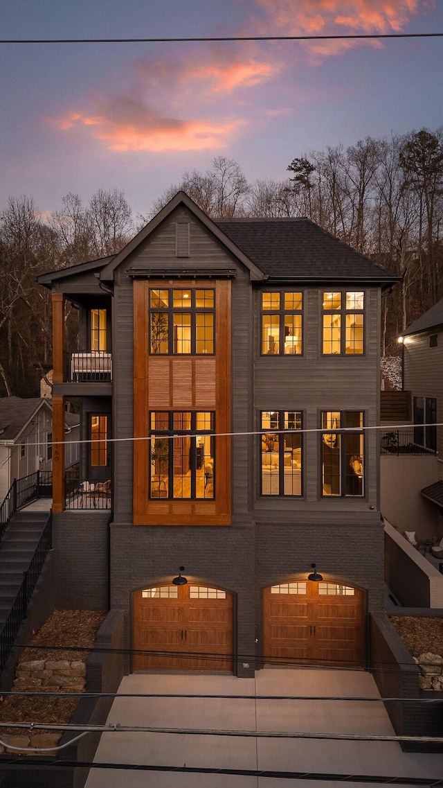 rear view of house with a garage, concrete driveway, and a balcony