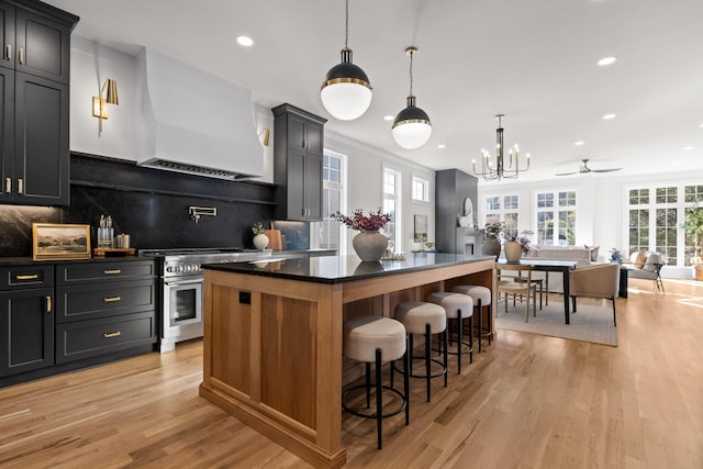 kitchen with a breakfast bar, a kitchen island, open floor plan, high end stainless steel range, and custom exhaust hood