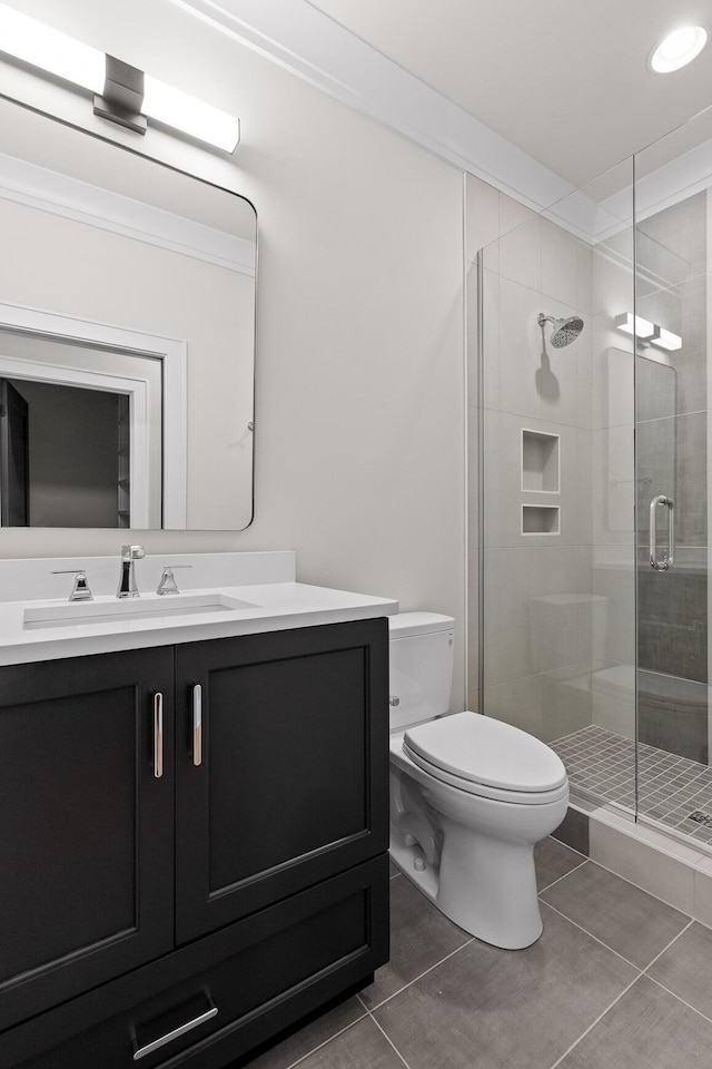 bathroom with a stall shower, toilet, tile patterned flooring, crown molding, and vanity