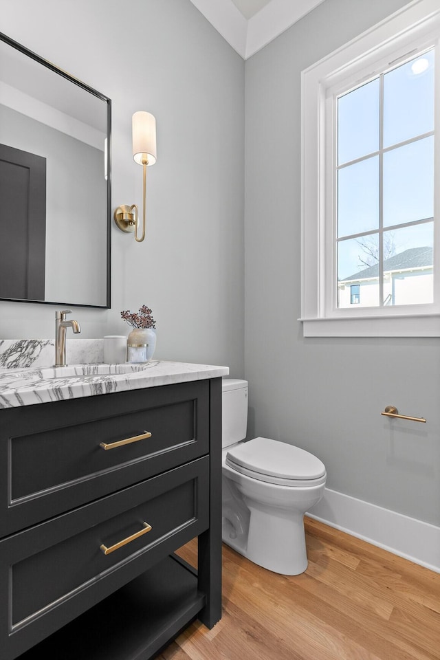 bathroom with vanity, wood finished floors, toilet, and baseboards