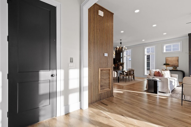 corridor featuring light wood-style floors, recessed lighting, and a chandelier