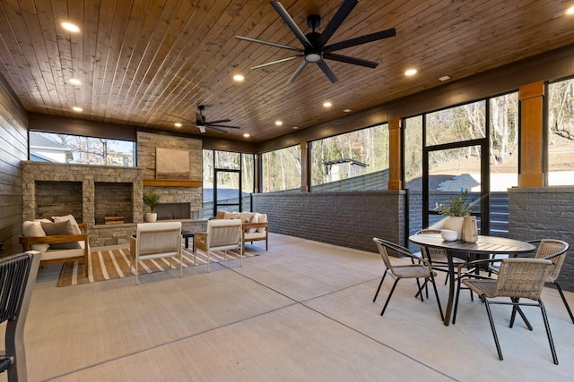 sunroom with wooden ceiling, ceiling fan, and an outdoor stone fireplace