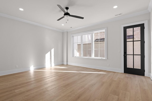 empty room with light wood finished floors, visible vents, a wealth of natural light, and ornamental molding