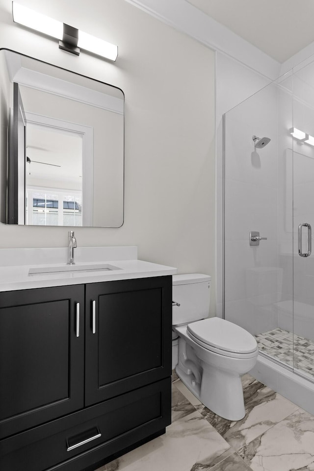 full bathroom featuring marble finish floor, a stall shower, vanity, and toilet