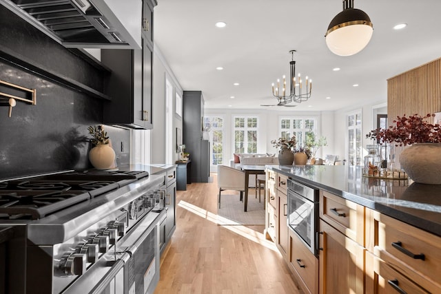 kitchen featuring wall chimney exhaust hood, decorative light fixtures, light wood-style floors, double oven range, and recessed lighting