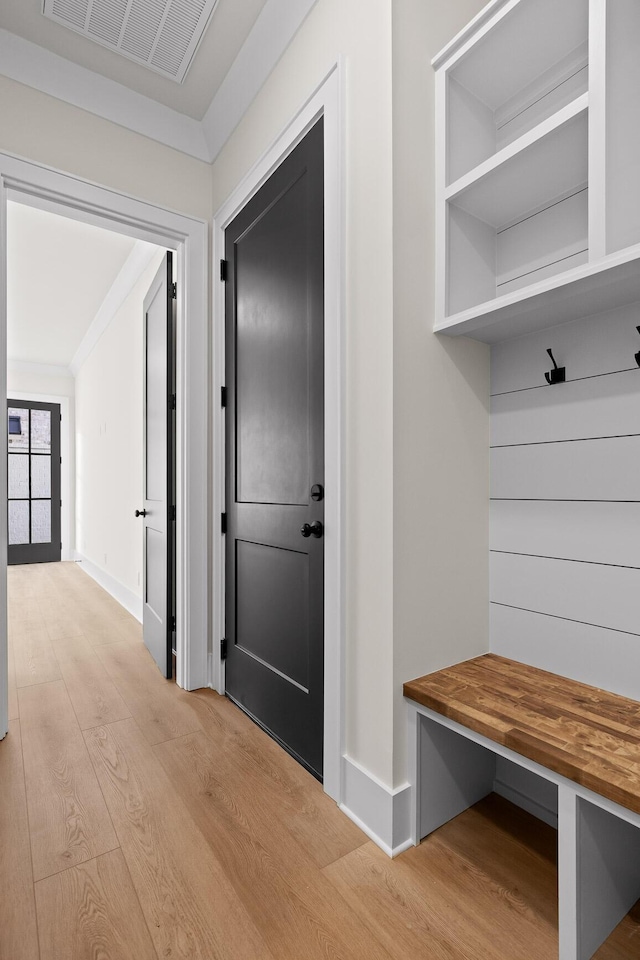 mudroom featuring light wood-type flooring, visible vents, crown molding, and baseboards