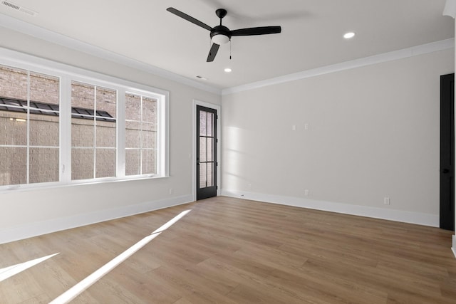 empty room featuring baseboards, light wood finished floors, visible vents, and crown molding