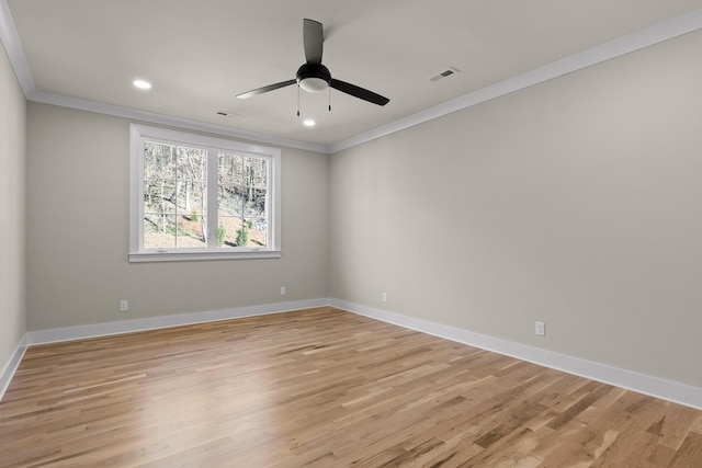 spare room with ornamental molding, light wood-style flooring, and baseboards