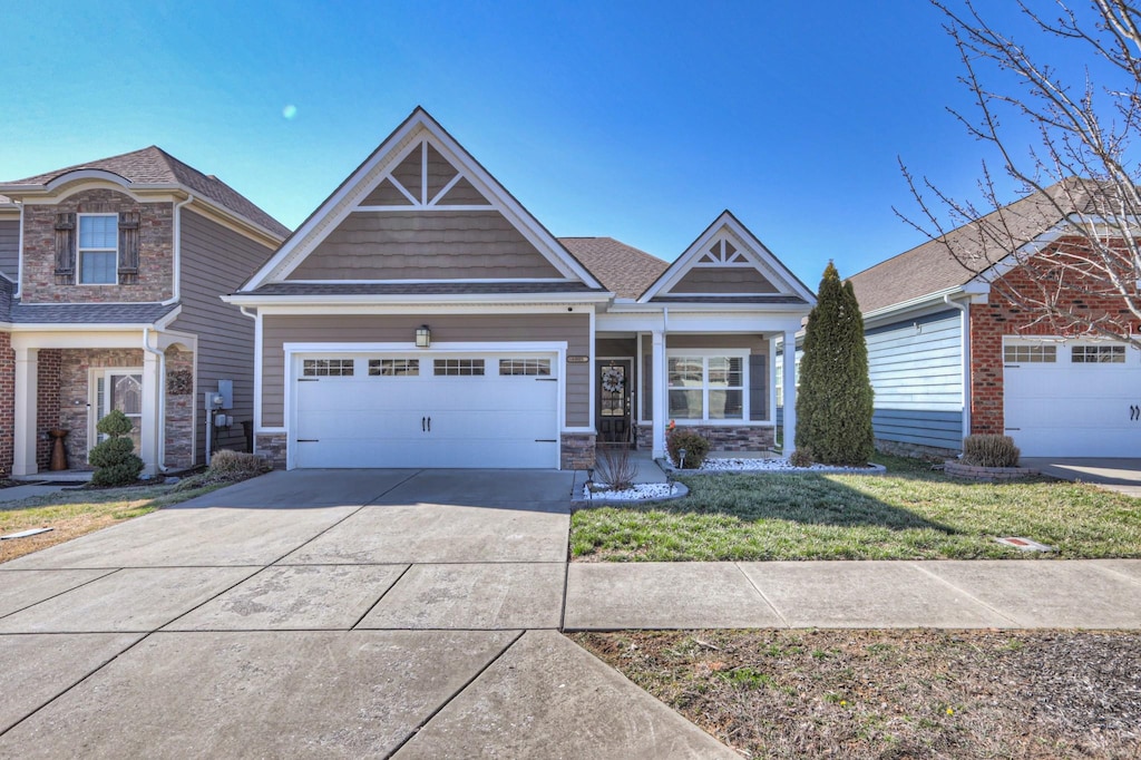 craftsman house with an attached garage, stone siding, driveway, and a front lawn