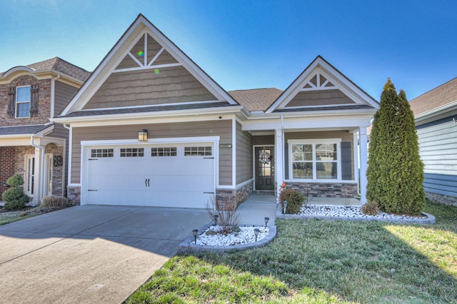 craftsman-style home featuring a garage, stone siding, driveway, and a front lawn