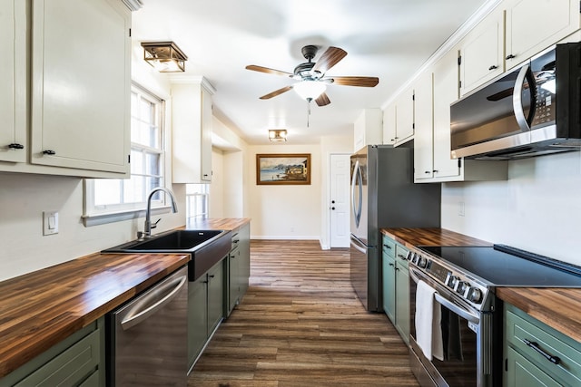 kitchen with butcher block countertops, appliances with stainless steel finishes, dark wood-style flooring, and a sink