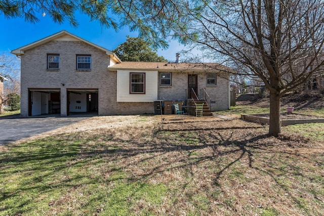 split level home featuring aphalt driveway, brick siding, an attached garage, and a front lawn