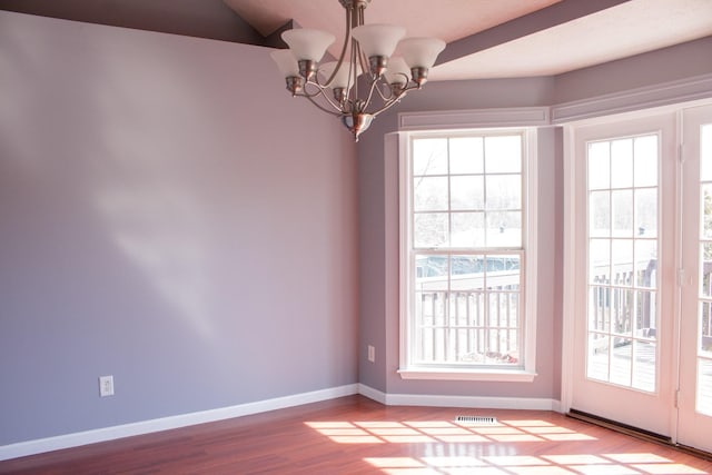 interior space featuring a healthy amount of sunlight, visible vents, a chandelier, and wood finished floors