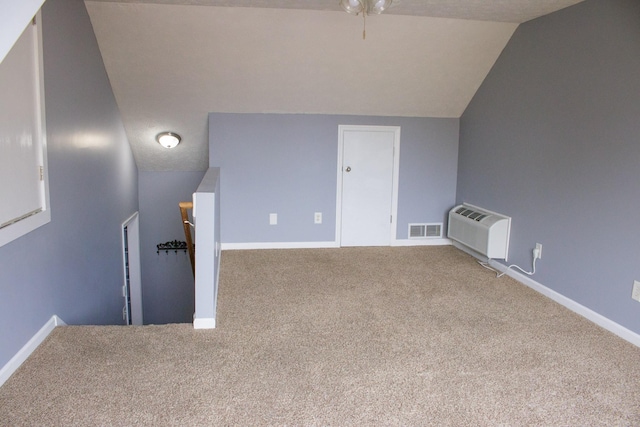 bonus room with a wall unit AC, visible vents, carpet flooring, vaulted ceiling, and baseboards