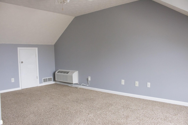 additional living space featuring carpet, visible vents, an AC wall unit, vaulted ceiling, and baseboards