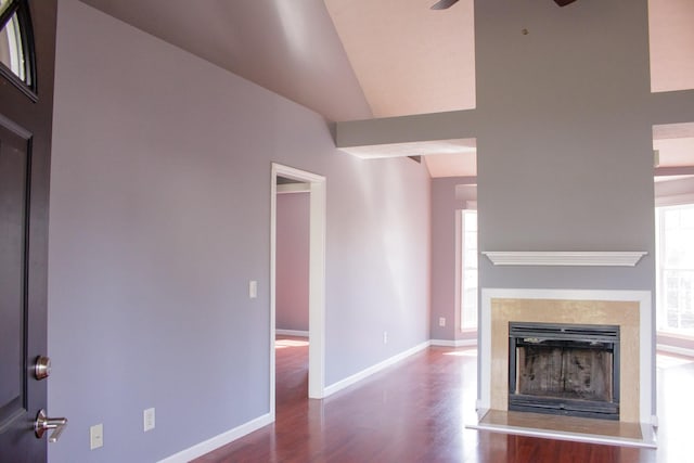 unfurnished living room featuring a ceiling fan, a fireplace with raised hearth, baseboards, and wood finished floors