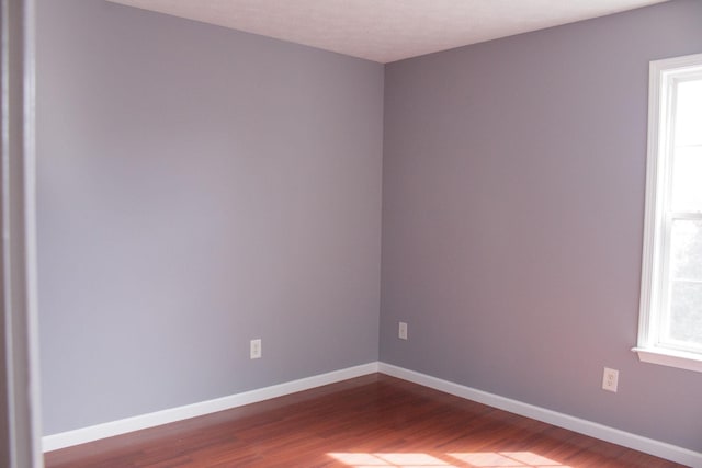 spare room with dark wood finished floors and baseboards