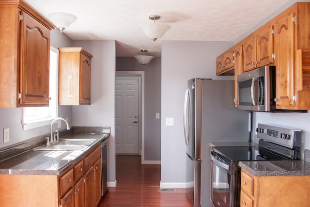 kitchen with dark wood-style flooring, a sink, visible vents, baseboards, and appliances with stainless steel finishes