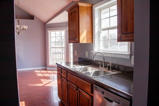 kitchen with dark wood-style floors, dark countertops, lofted ceiling, stainless steel dishwasher, and a sink