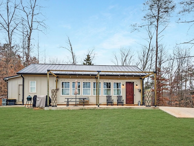 view of front of house featuring board and batten siding, a front yard, a standing seam roof, and metal roof