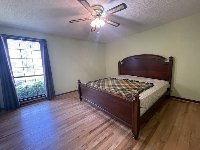 bedroom featuring a textured ceiling, ceiling fan, wood finished floors, and visible vents